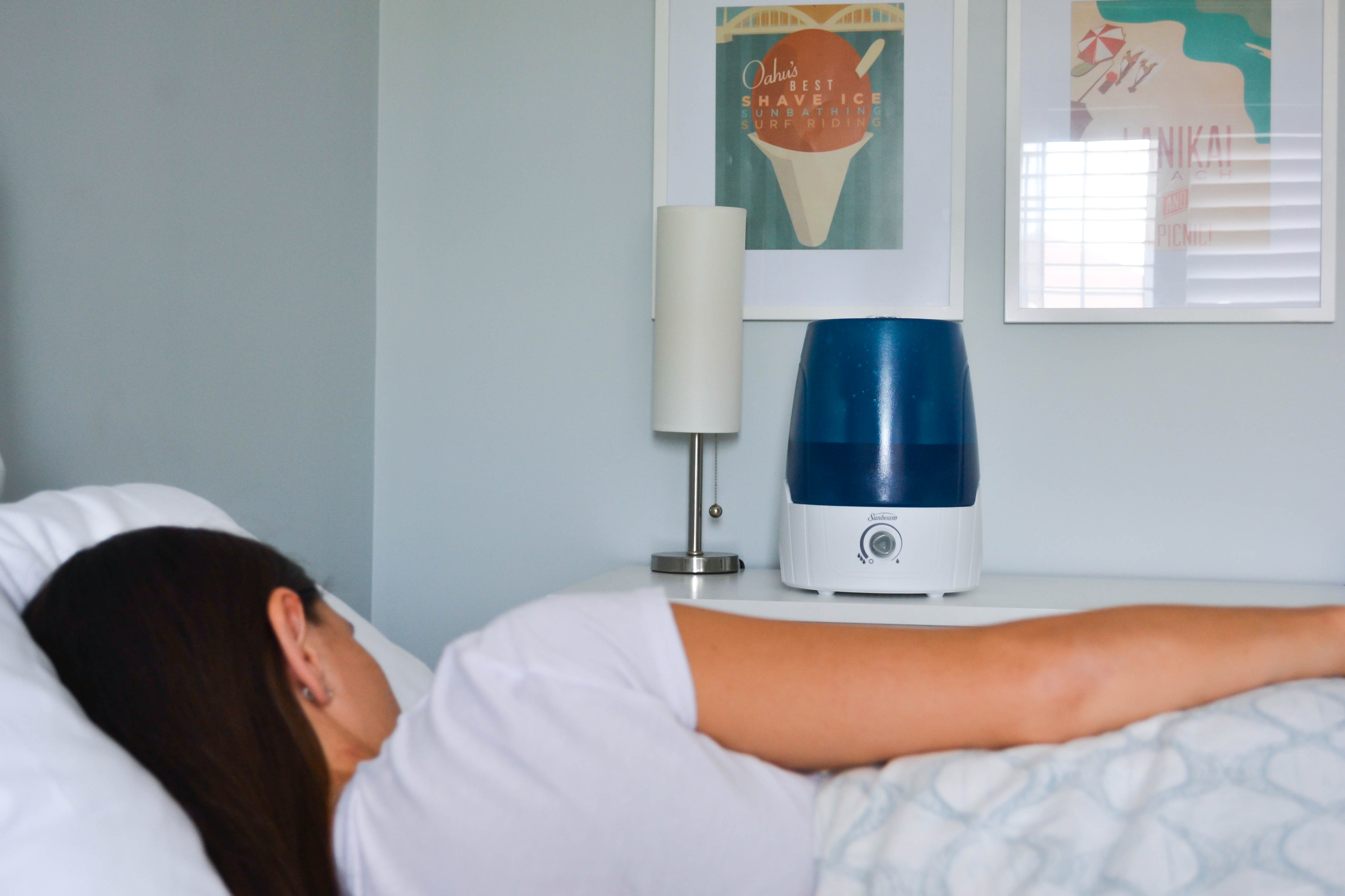 Woman sleeping in bed next to humidifier
